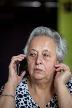 Evde akıllı telefondan konuşan son sınıf öğrencisi bir kadının portresi..