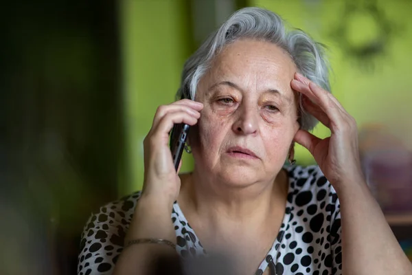 Portrait senior woman talking on smartphone at home.