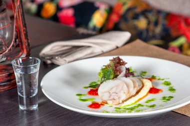 Masada bir bardak votka ve balık tabağı.