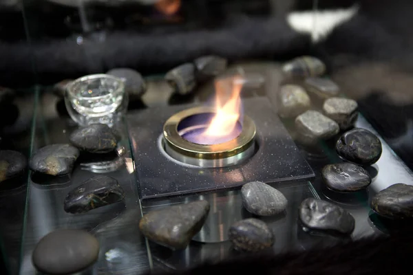Bioethanol fueled portable fireplace burning at home, for live fire at home, no chimney and mantelpiece is needed. Liquid bio ethanol burns in cup. Round shaped glass with stones inside — Stock Image Bioethanol Fueled Portable Fireplace Burning Home Live Fire Home Chimney Royalty Free Stock Photos