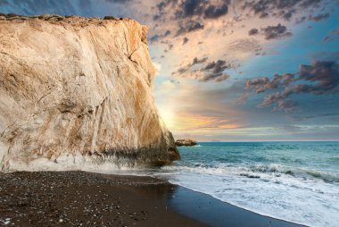 Okyanus sahilinde gün batımında kayalık bir uçurumun altında