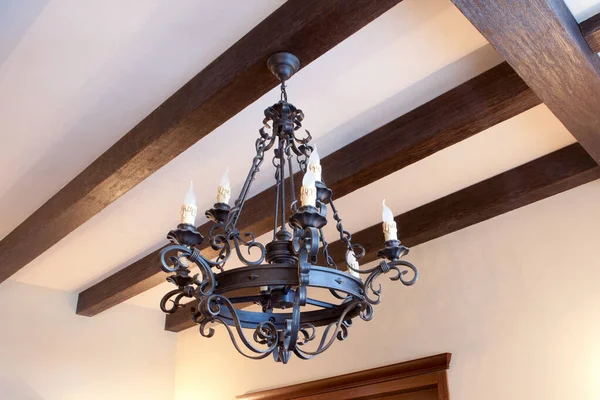 Yuvarlak siyah işlemeli demir avize ve evde ampuller var.