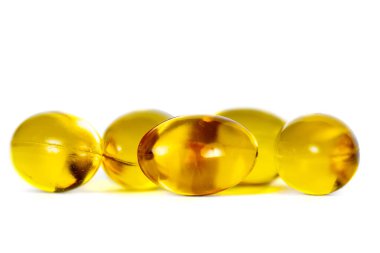 D vitamininin sarı kapsülleri, beyaza izole edilmiş altın hapların makro yakın çekimi