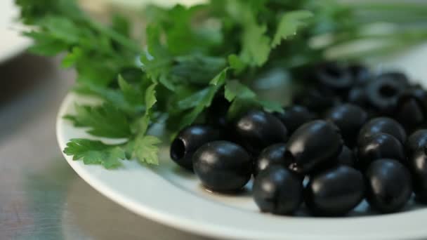 Oliver på plattan. Persilja. Skär övriga-paprika på en vit platta. Ingredienser för att göra sallad. Skörda mat. Restaurang, kök. Röd paprika. Bulgariska röd paprika. — Stockvideo