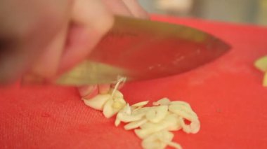 Şef sarımsak dilimleri. Bıçak, doğrama kurulu, sarımsak. Hızlı kesme sebze. Sarımsak. Kızartma için sarımsak. Aşçı eller.