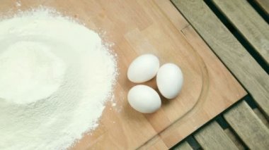 Aşçı bir yumurta un haline tatili. Hamur bir ahşap tahta üzerinde yemek. Masada, tavuk yumurta un. Hamburger için rulo, ekmek hazırlar. Kepekli ekmek yemek.