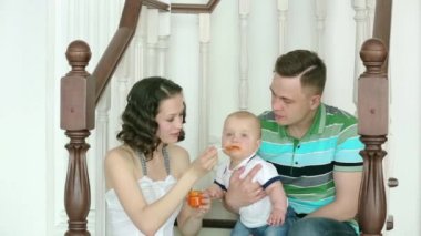 Anne Çocuk yayınları ve babam onu tutuyor. Mutlu bir aile. Anne baba ve 6 aylık bebek. Merdivenlerde evde oturan aile.