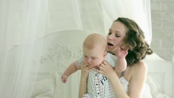 Mamá juega con el niño. Una familia joven. Hija y madre de seis meses. Feliz mamá. Madre e hijo divirtiéndose. El niño sonríe . — Vídeos de Stock