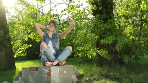 Menina bonita em jeans roupas fazendo selfie no telefone no parque . — Vídeo de Stock