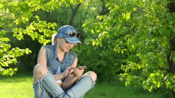 Красивая девушка в джинсах разговаривает по телефону в парке . — стоковое видео