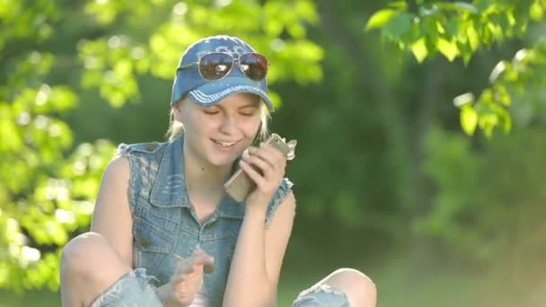 Parkta telefonda konuşurken kot pantolon giysili güzel kızı. — Stok video