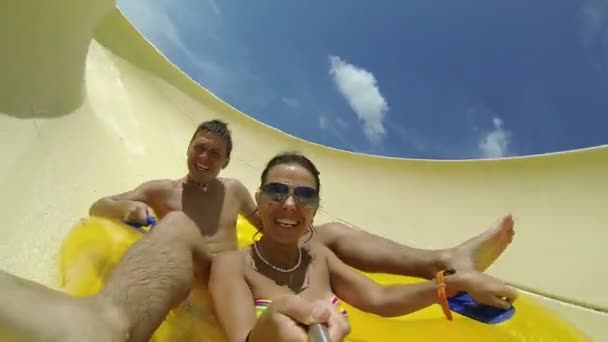 Couple sliding down a water slide at public swimming pool. — Stock Video