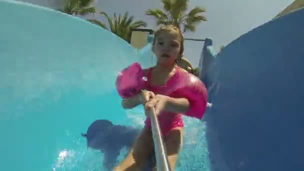 Sonriente niña jugando en una casa inflable de la despedida de la diapositiva al aire libre — Vídeos de Stock