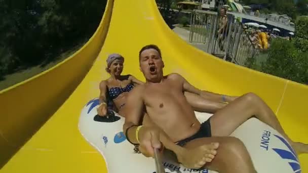 Couple sliding down a water slide at public swimming pool. — Stock Video