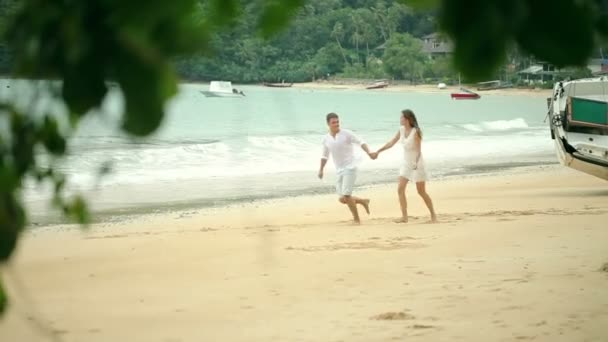 Щаслива пара біжить на пляжі. Подорожуйте разом . — стокове відео