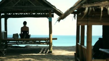 Pavilion plaj önünde Yoga pratik siluet genç kadın.