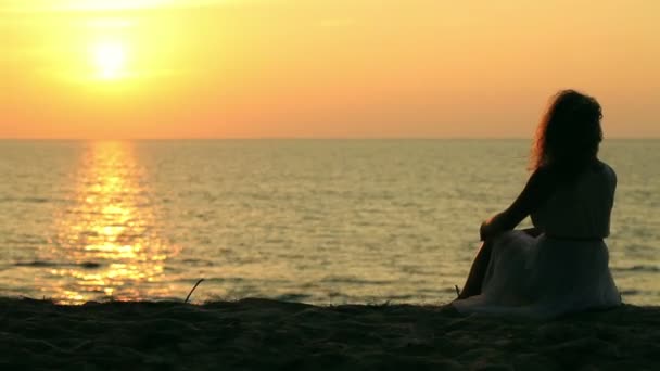 Красиві жінки, що сидять на фоні заходу сонця на пляжі . — стокове відео