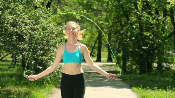 여자 운동 야외 활동을 하 고입니다. 여자는 미소와 함께 점프 밧줄에 점프입니다. 젊은 여자는 공원에서 연습을 하 고. 슬림 바디와 귀여운 소녀. — 비디오