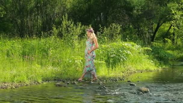 Молодая красивая женщина с цветочным венком у реки. Красивая девушка гуляет по реке . — стоковое видео