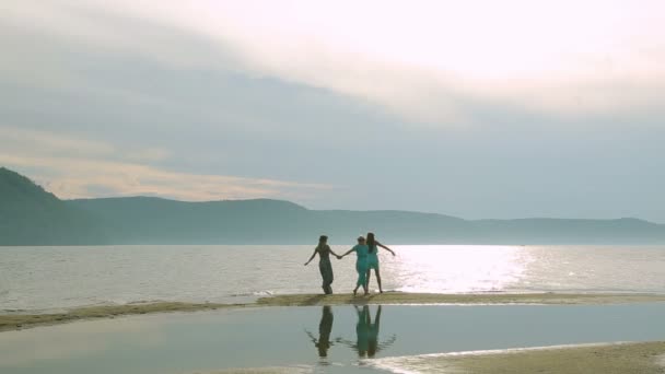 Partij en mensen concept - groep glimlachend tienermeisjes springen op strand. Silhouet van drie jonge vrouwen om rond te rennen en springen op het strand bij zonsondergang. — Stockvideo