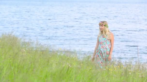꽃 화 환을 입고 풀밭에 걷는 아름 다운 소녀. 성인 영입니다. 인쇄 꽃과 세련 된 드레스를 입고. — 비디오