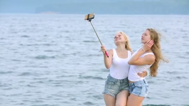 Dos amigas mujeres tomando selfie con teléfono móvil cerca del río. Dos chicas jóvenes disfrutando cerca del río y tomando selfie usando un teléfono inteligente . — Vídeos de Stock