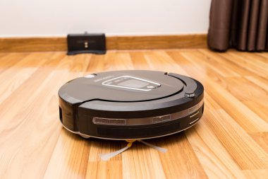 Robotic vacuum cleaner on wood parquet floor.