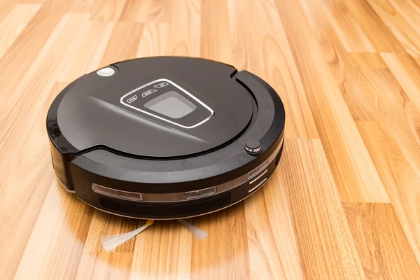 Robotic vacuum cleaner on wood parquet floor. — Stockfoto