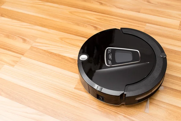 Robotic vacuum cleaner on wood parquet floor. — Stock Photo, Image