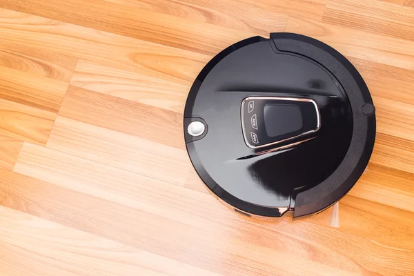 Aspirador robótico no chão de parquet de madeira . — Fotografia de Stock