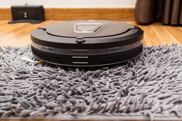 Robotic vacuum cleaner on wood parquet floor — Stockfoto