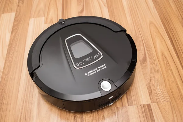 Robotic vacuum cleaner on wood parquet floor — Stock Photo, Image