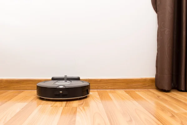 Robotic vacuum cleaner on wood parquet floor — Stockfoto