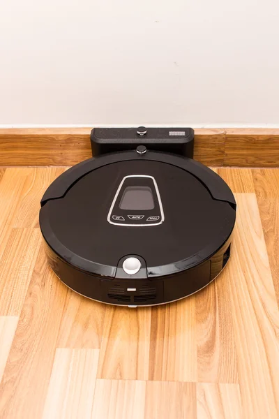 Robotic vacuum cleaner on wood parquet floor — Stock Photo, Image