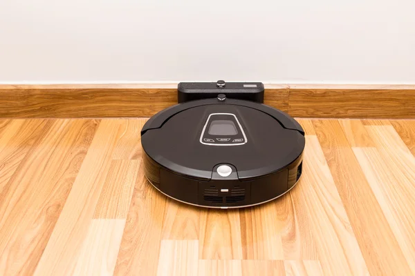 Robotic vacuum cleaner on wood parquet floor — Stock Photo, Image