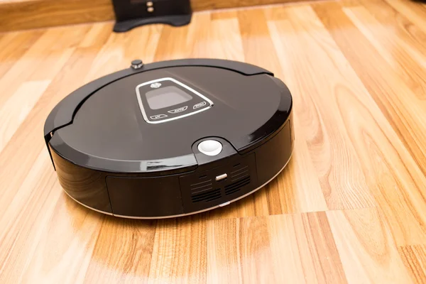 Robotic vacuum cleaner on wood parquet floor — Stockfoto