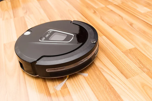 Robotic vacuum cleaner on wood parquet floor — Stock Photo, Image