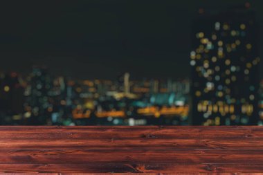 Ürün montaj şablonu grafik kaynağı için gece şehir görünümlü şehir bulanık arka plan tahtadan masa üstü forgoundu.