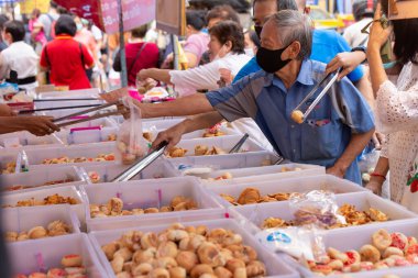 people buy vegetarian food at Yaowarat J Festival Bangkok Chinatown street, shop are decorated with yellow flag with symbols of eat for merit, no animal meat sign. 18 October 2020, Bangkok,THAILAND.