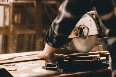 Carpenter, DIY atölyesinde ahşap mobilya yapmak için elektrikli ahşap kesici kullanıyor..