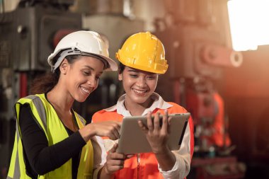 Fabrika mühendisi kadınlar birlikte çalışıp tablet gülüşü kullanıyorlar.