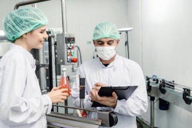 Gıda ve içecek fabrikası ISO kalite kontrol ekibi fabrika üretim hattında çalışıyor, hijyen kontrolü yapıyor ve standart denetimi işliyor.