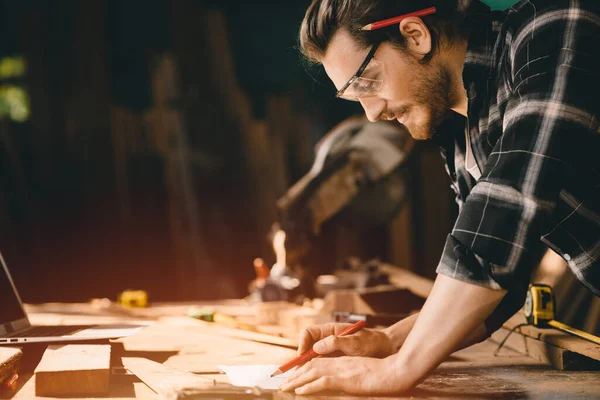 Happy Carpenter smiling to sketch design wooden furniture in wood workshop professional look high skill real authentic handcrafted working people.