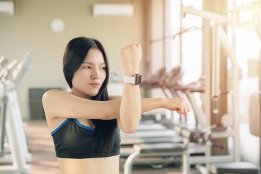 Genç Asyalı sağlıklı kadın kol kaslarını esnetiyor, egzersiz yapmadan önce ısınıyor..