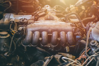 Eski araba motoru yedek parçası kapalı egzoz manifoldu ya da başlıklar çelik araç makinesi kirli yağ grunge satışı için garajda yağ