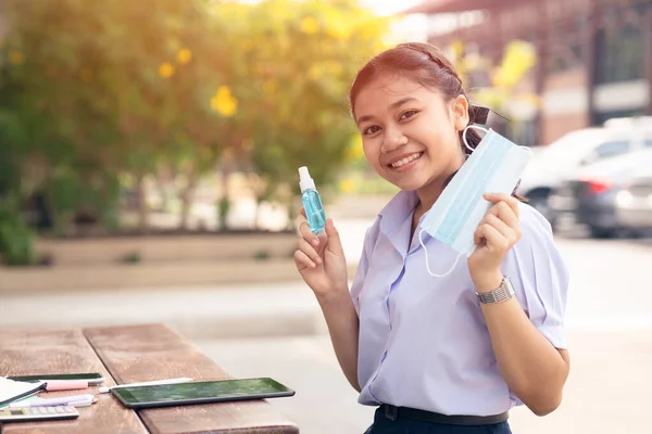 Healthy Asian Student Happy using Face Mask and Alcohol Spray in School for Corona Virus(COVID-19) Protection.