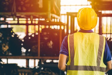 Erkek mühendis, ağır endüstriyel metal fabrikasındaki raflara bakıyor.