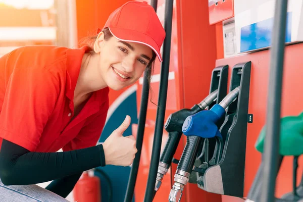 Gas station women worker staff Thumbs up at fuel nozzle dispensers happy service working refill cars gasoline