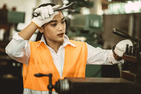 疲れた女労働者金属機械で汗を拭く熱い工場でアジアの労働者のハードワーク — ストック写真