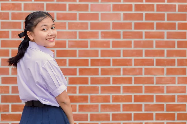 可愛いです女の子ティーン学生とともに制服幸せな笑顔とともに学校キャンパスレンガの壁のコピースペース — ストック写真